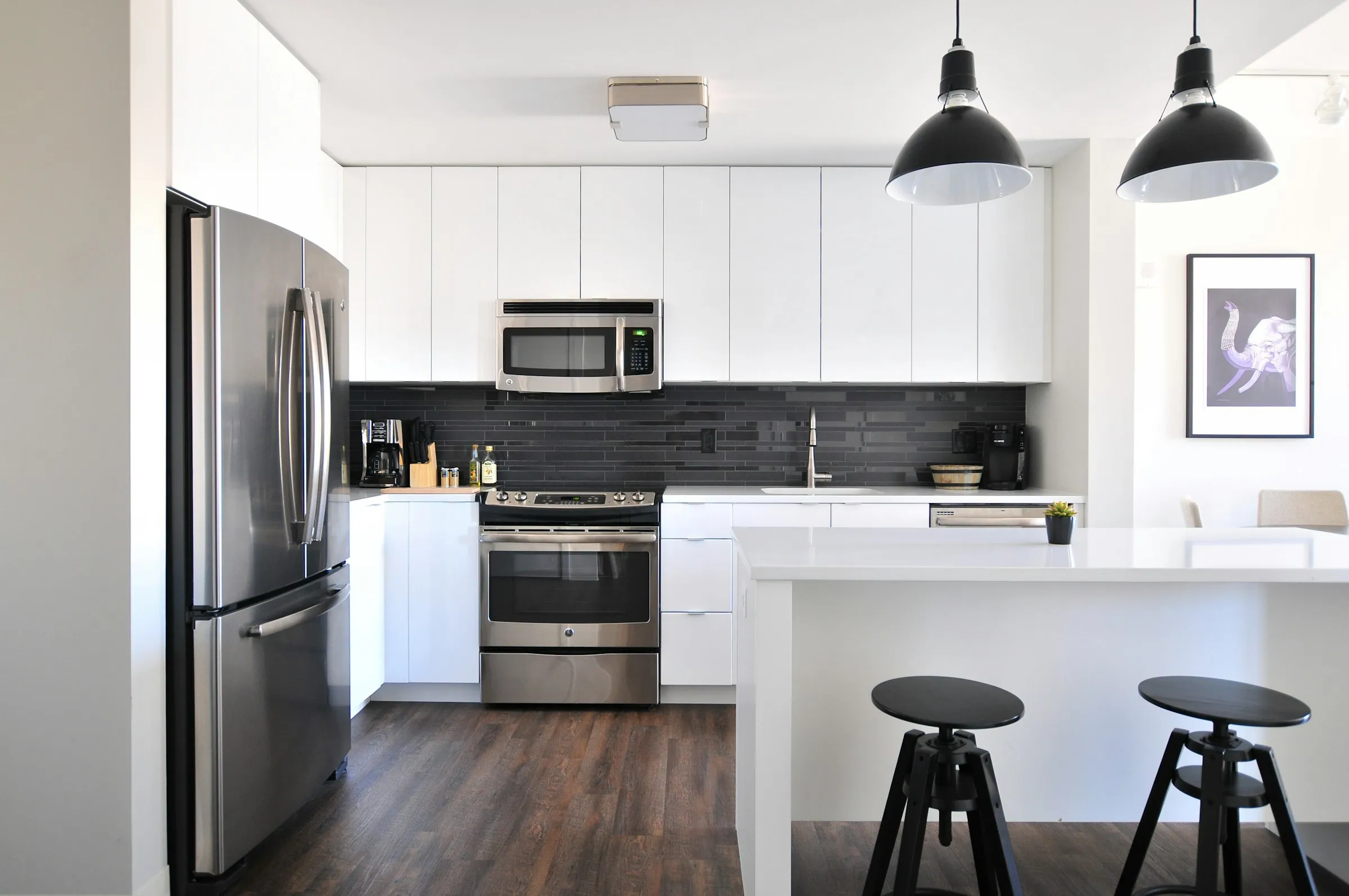 Cocina blanca con frente oscuro, isla y taburetes