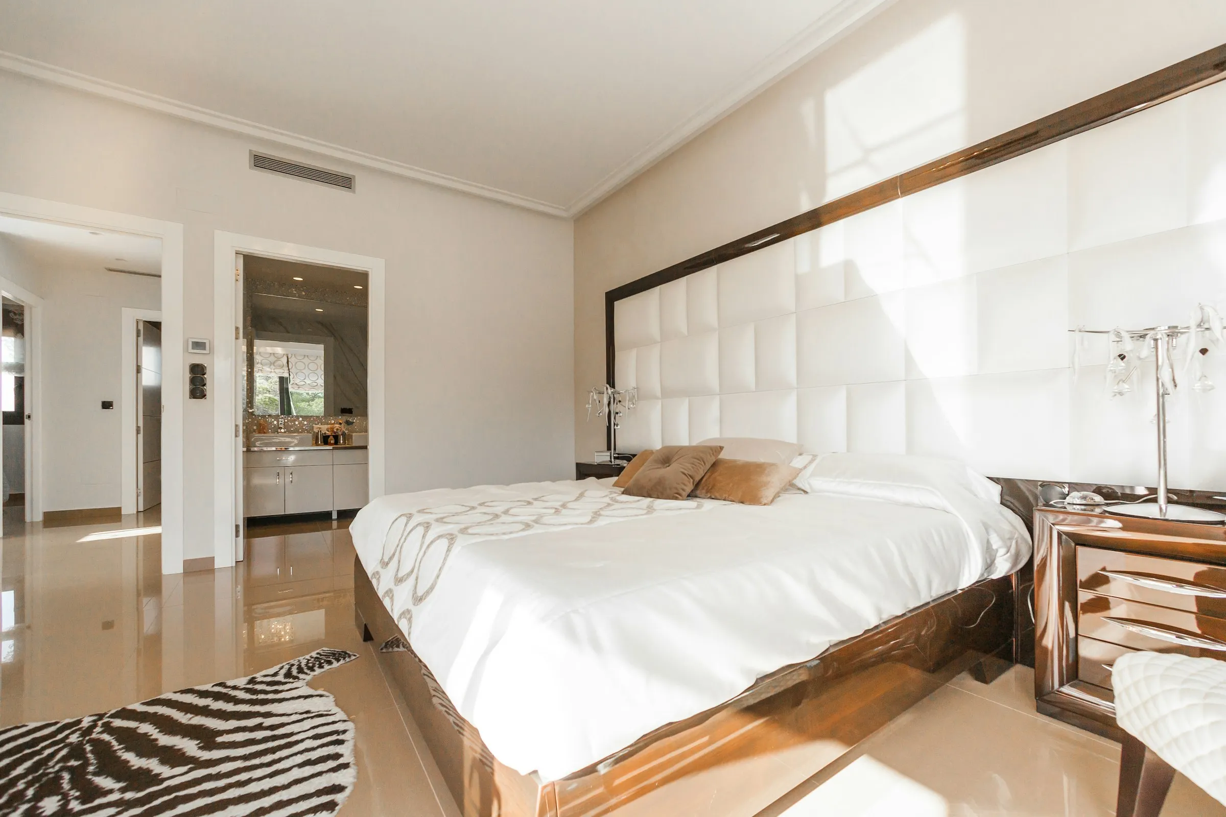 Dormitorio blanco con cabecero acolchado y luz lateral