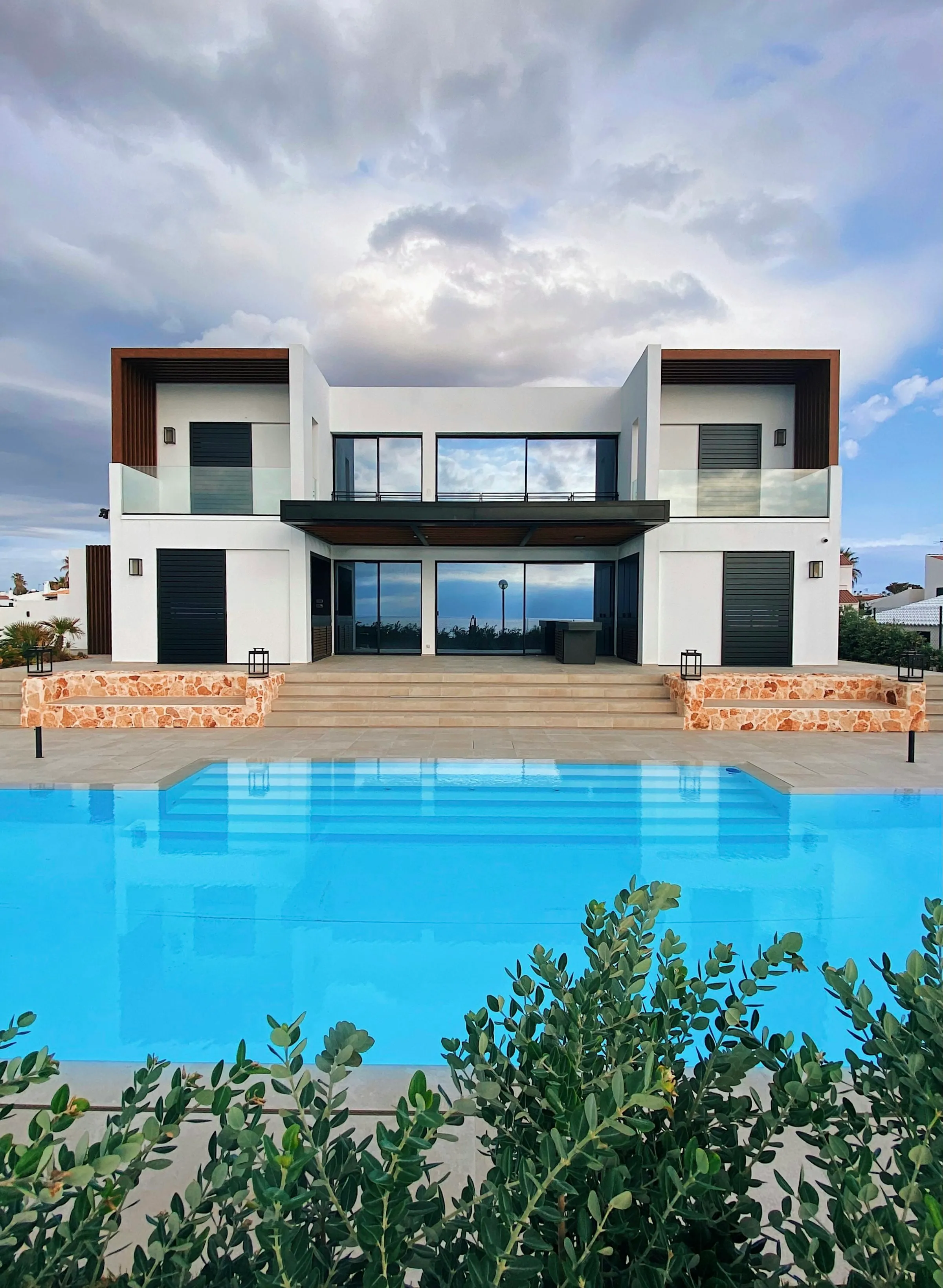 Casa moderna de vidrio con piscina iluminada al anochecer